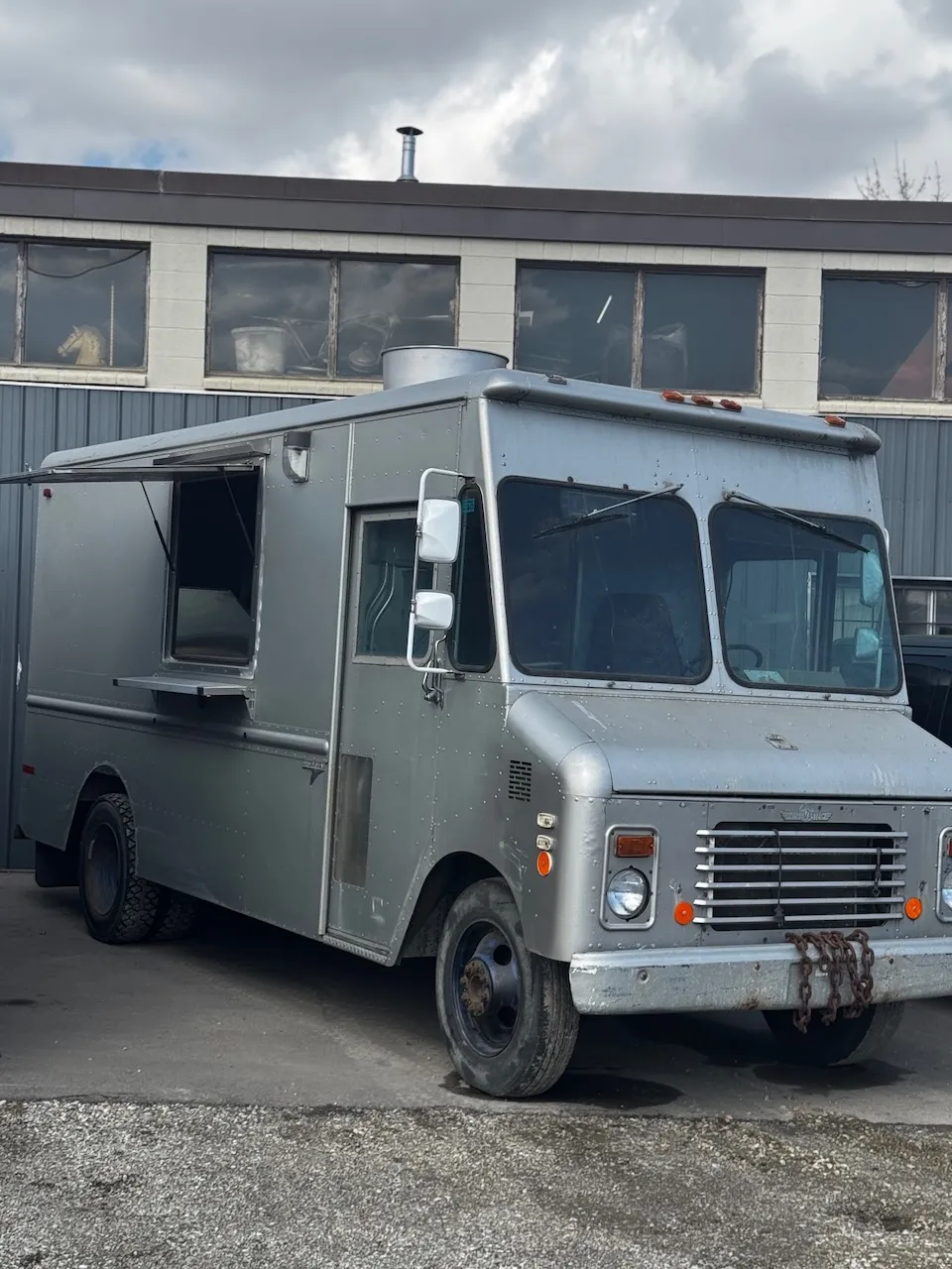 The silver step-van food truck for sale, with its serving window open