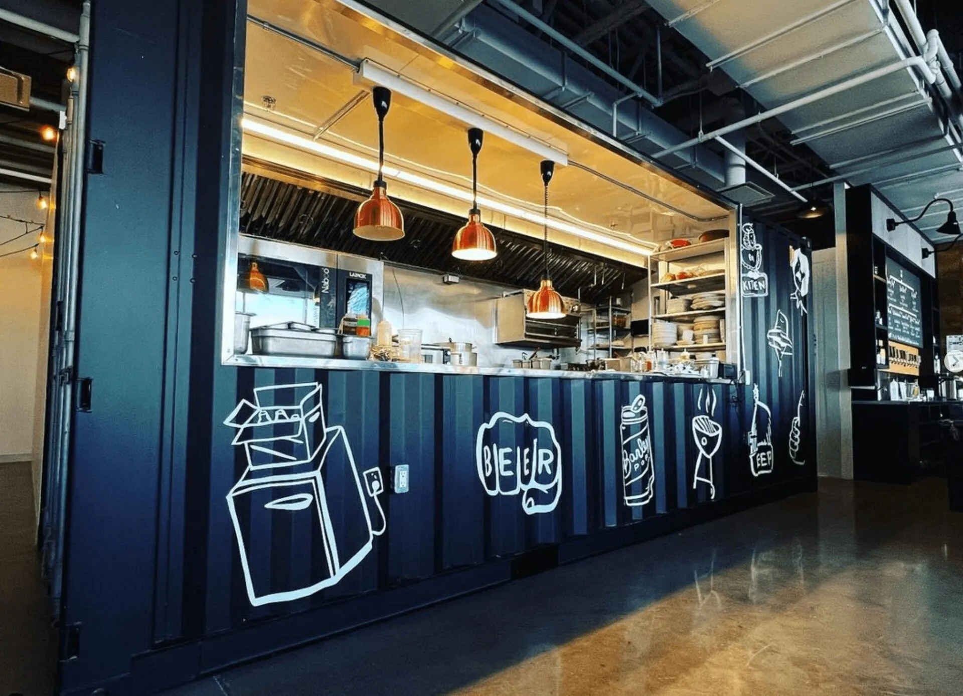 Shipping-container kitchen with pendant lights and hand-drawn food illustrations