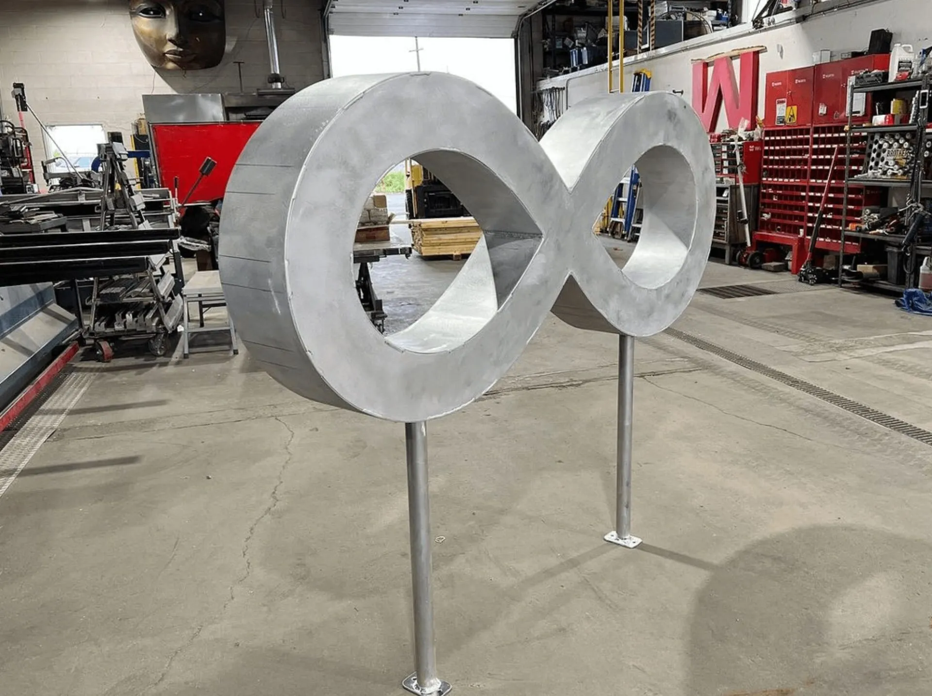 Large brushed-metal infinity sign on two posts in the shop